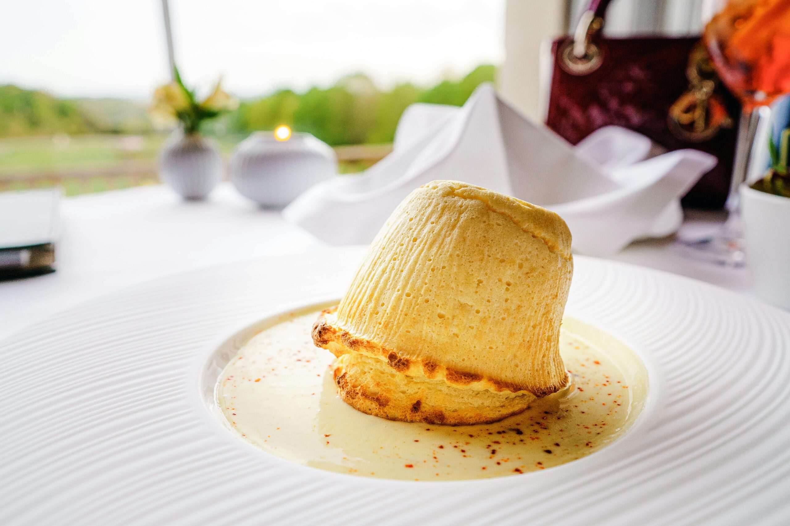 Indulge in a mouthwatering soufflé dessert elegantly presented on a table with vibrant background.