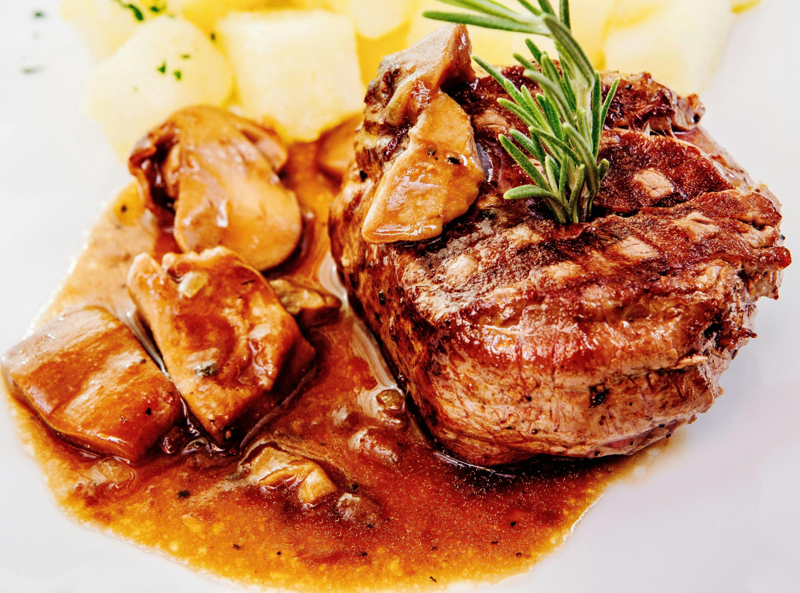 Savory steak with mushroom sauce and potatoes, garnished with rosemary.
